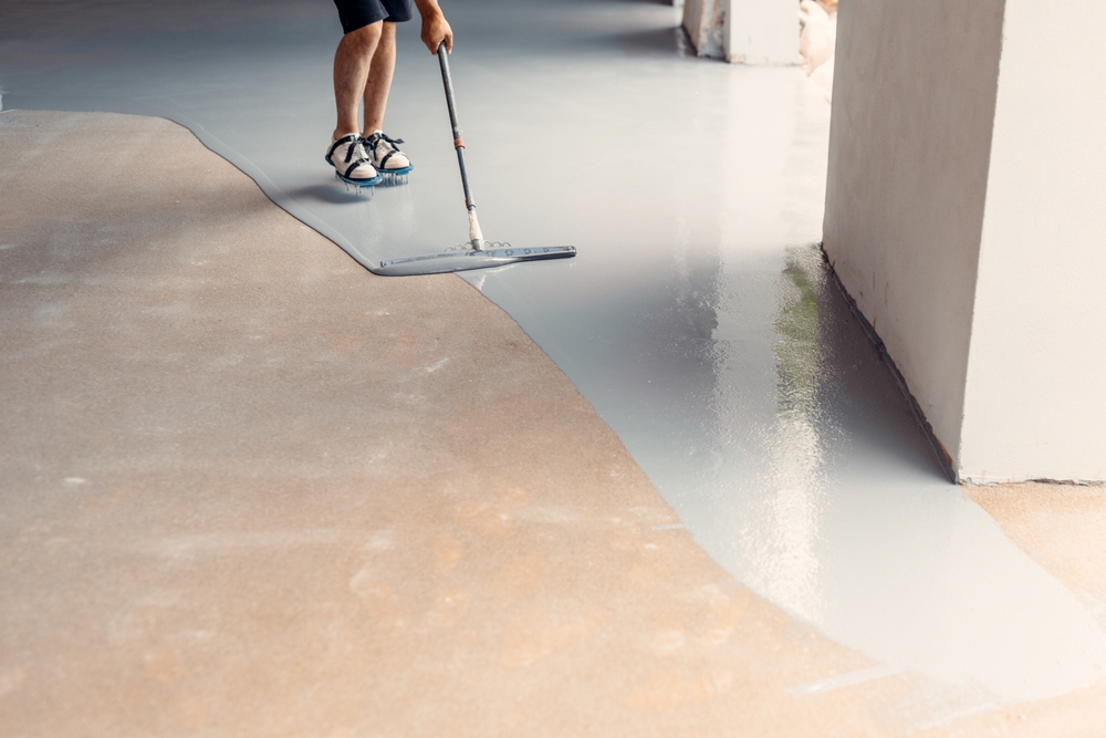 Epoxy floor installation over existing concrete using roller and rubber spatula